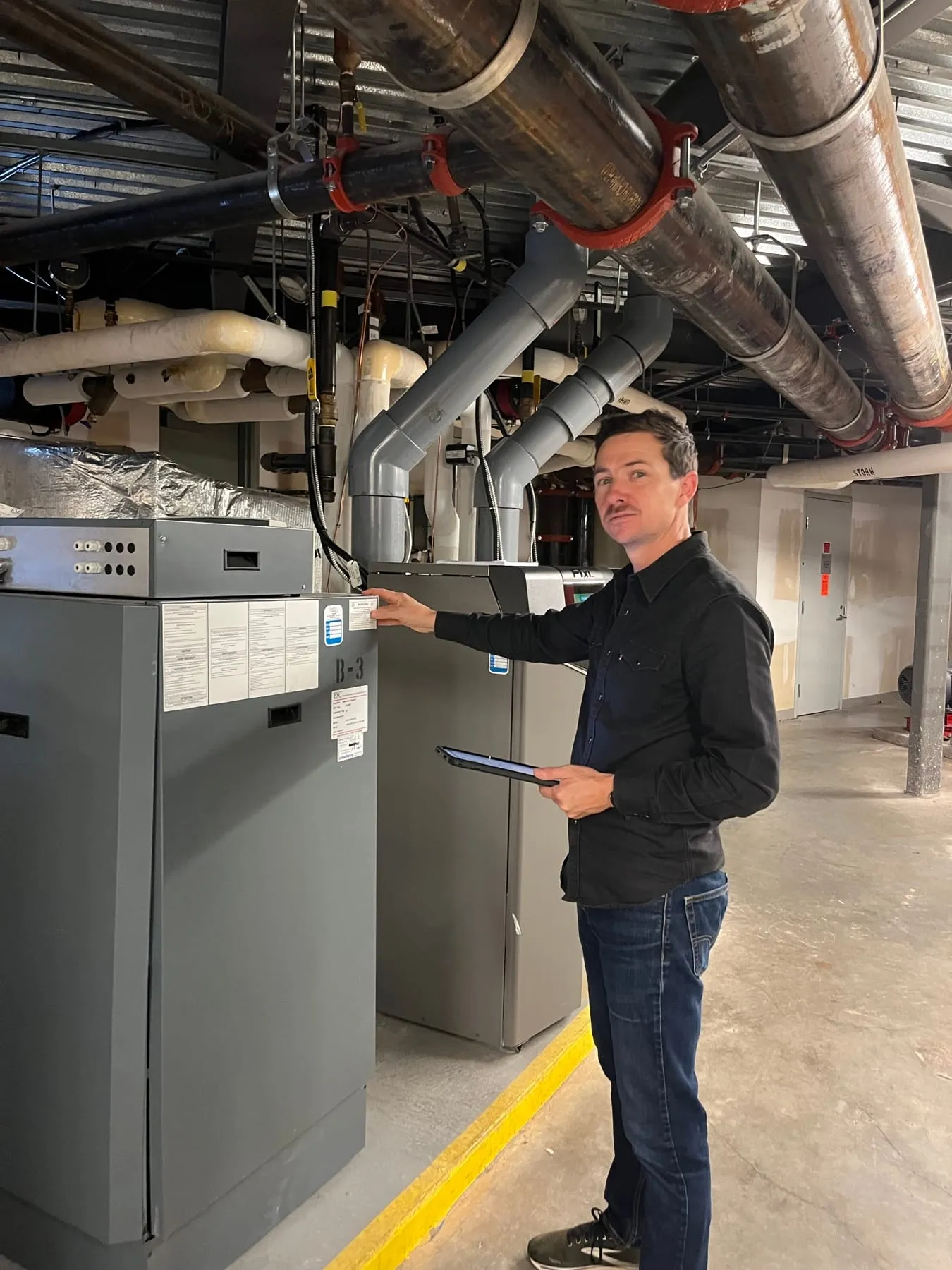 Chris Farrar reading an equipment label in a strata mechanical room
